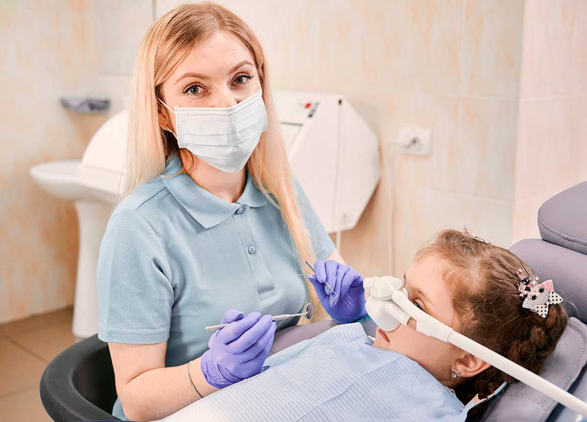 Pediatric dentist examining little girl’s teeth
